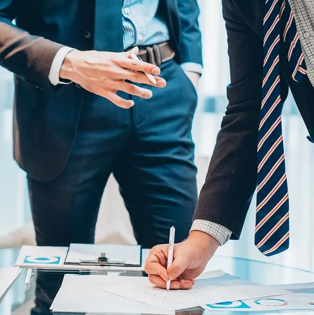 recorte hombres de negocios con mesa de cristal de papeleo y firmas