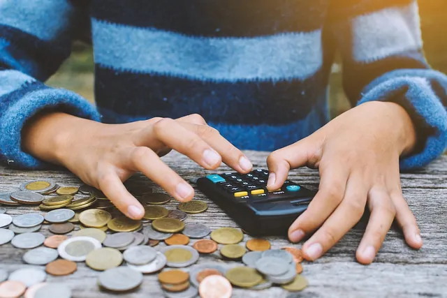 recorte manos con calculadora y monedas sobre la mesa