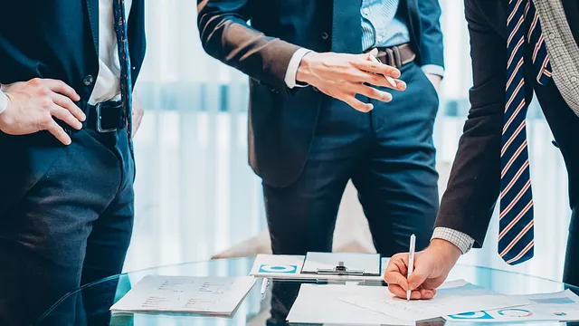 recorte hombres de negocios con mesa de cristal de papeleo y firmas